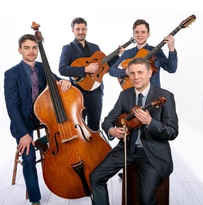 A group of four smartly dressed musicians with double bass, two guitars and violin.